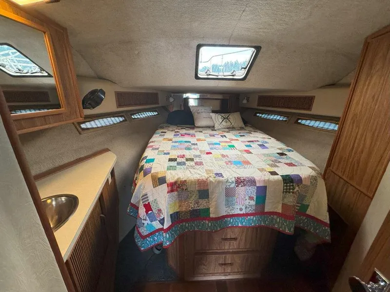 Slide: The Image of 1985 Sea Ray 390 Sedan Bridge cabin with bed, quilt, and wooden cabinetry. - 26