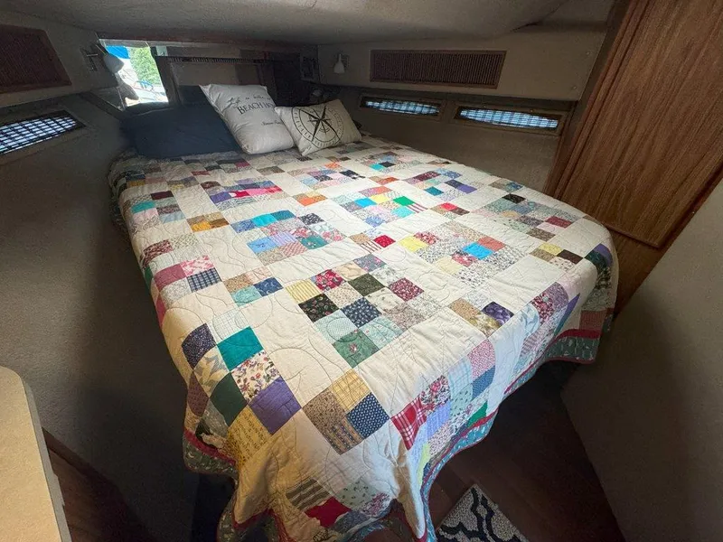 Slide: The Image of 1985 Sea Ray 390 Sedan Bridge cabin with a colorful patchwork quilt on the bed. - 28