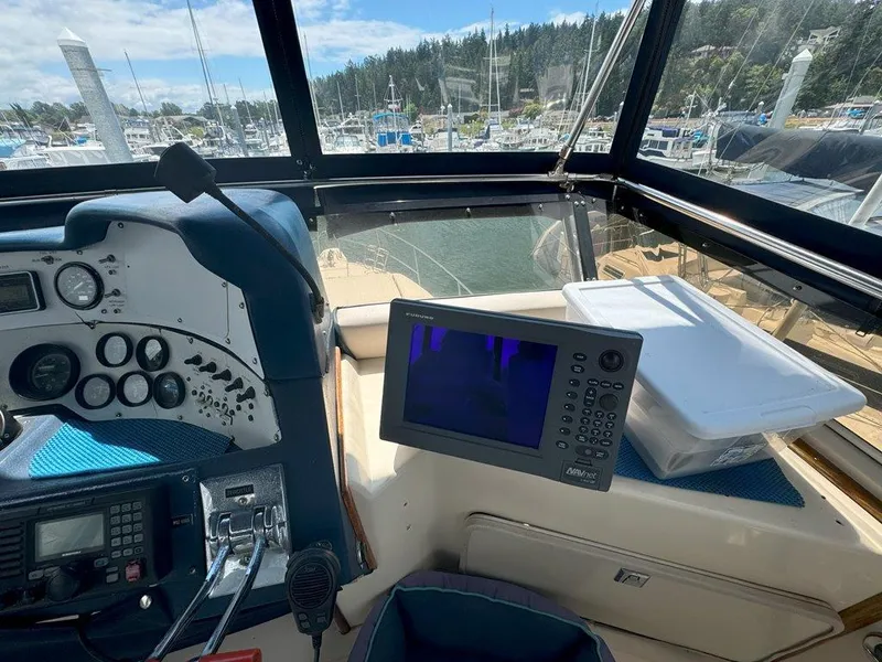Slide: The Image of 1985 Sea Ray 390 Sedan Bridge helm with navigation equipment and marina view. - 9