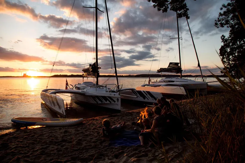 Slide: The Image of Sunset by the lake with Dragonfly 25 sailboats and people relaxing on the shore. - 2