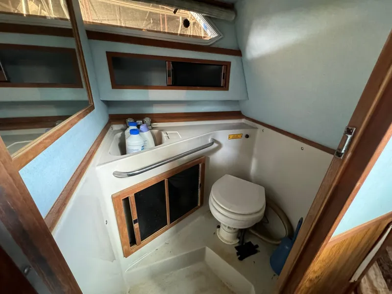 Slide: The Image of 1988 Sea Ray Sundancer 268 boat bathroom with toilet, sink, and storage cabinets. - 11