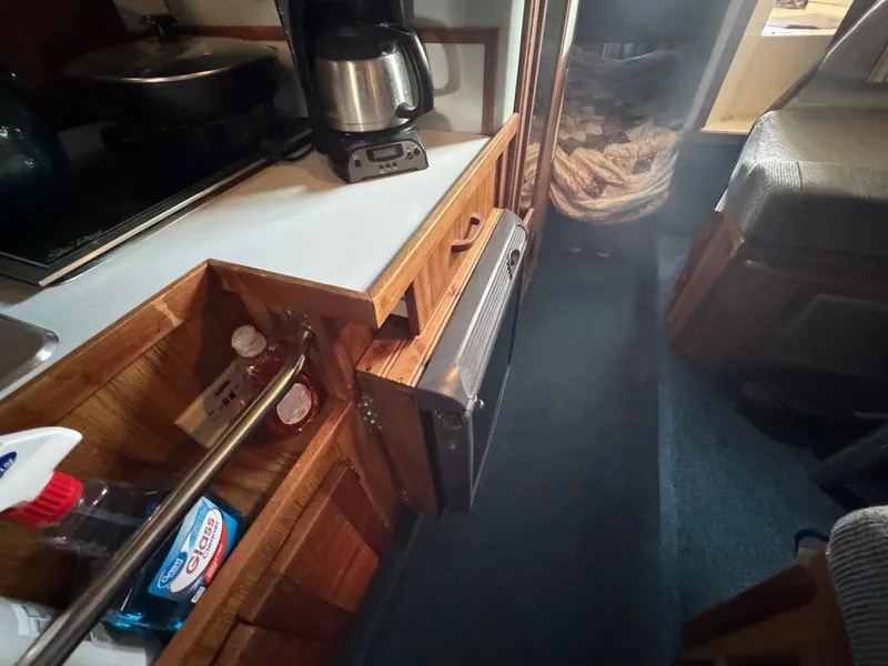 Slide: The Image of Interior of 1988 Sea Ray Sundancer 268 showing kitchen area with coffee maker and cleaning supplies. - 13