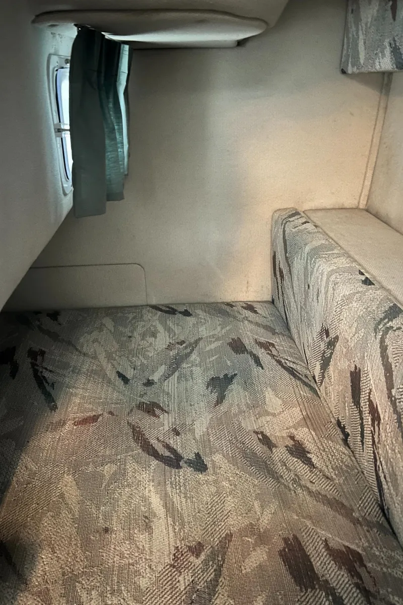 Slide: The Image of 1994 Chris-Craft 262 Crowne cabin interior with patterned upholstery and small window. - 12