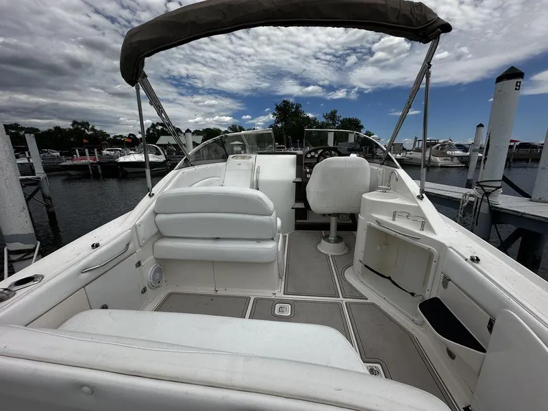 Slide: The Image of 2005 Regal Commodore 27 boat interior at marina, white seating, helm, and open storage. - 16