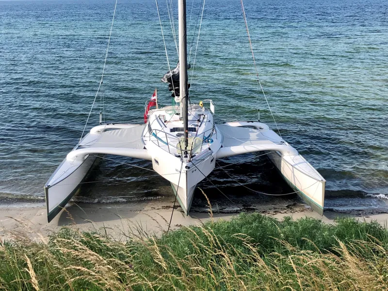 Slide: The Image of Sleek Dragonfly 28 trimaran beached on a sandy shore, 2026 model. - 2