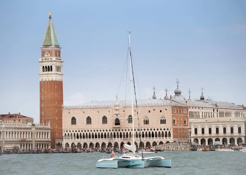 Slide: The Image of Sailboat Dragonfly 32 in Venice, 2026, with historic architecture and bell tower in background. - 4