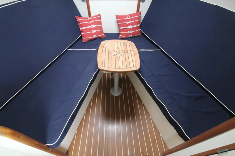 Slide: The Image of 2007 Luhrs 28 Open cabin with blue seating, wooden table, and nautical-themed cushions. - 13