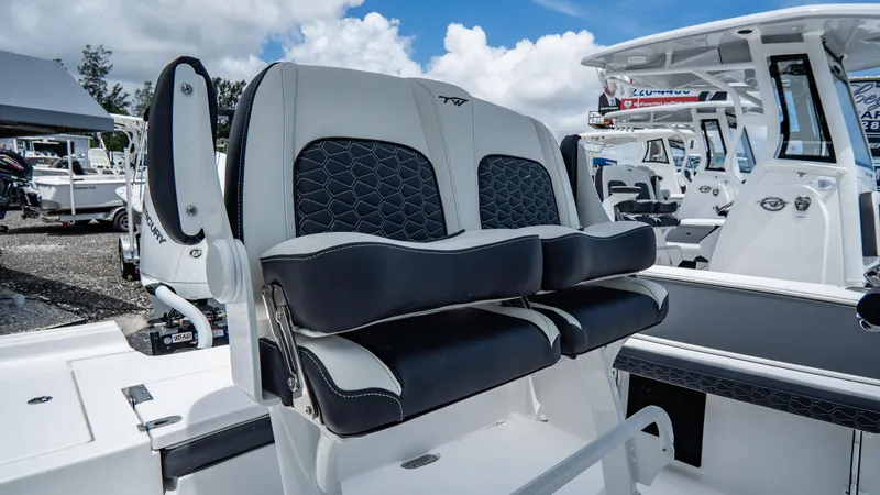Slide: The Image of 2025 Tidewater 2300 Carolina Bay boat with dual captain's chairs, docked under a blue sky. - 8