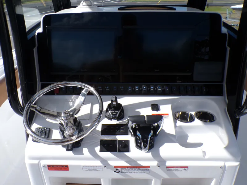 Slide: The Image of Control console of the 2025 Sea Hunt Ultra 305 SE boat with steering wheel and navigation screens. - 11