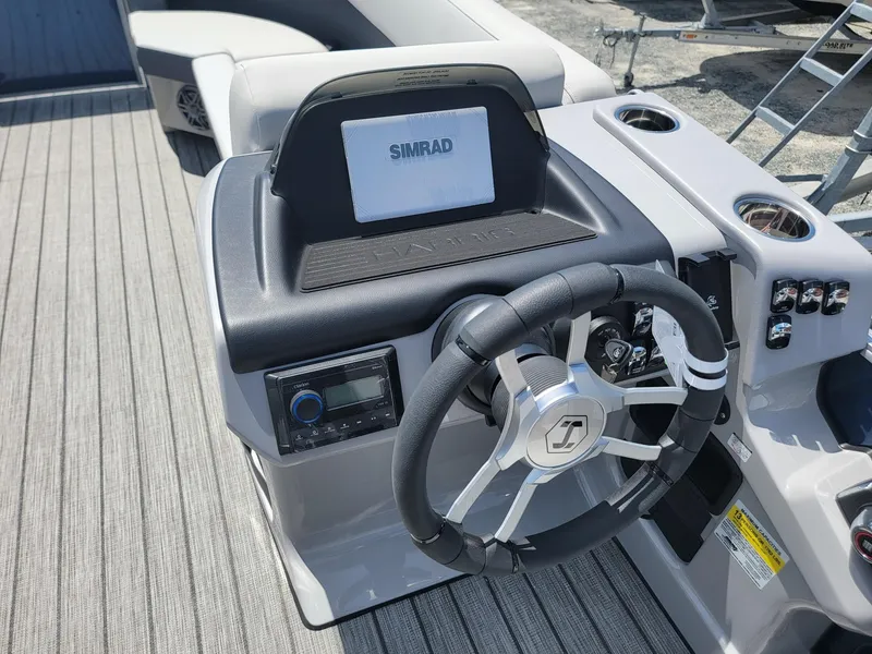 Slide: The Image of 2025 Harris Cruiser 210 boat dashboard with steering wheel and Simrad display. - 13