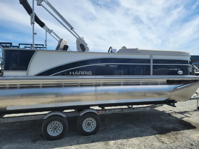 Slide: The Image of 2025 Harris Cruiser 210 pontoon boat on a trailer under a blue sky. - 5