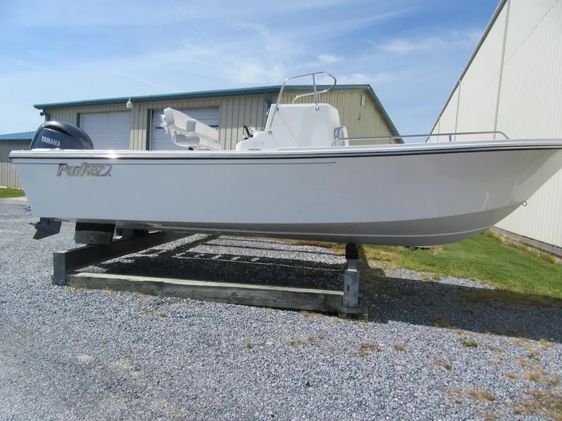 Slide: The Image of 2025 Parker 2300 SE CC boat on a wooden stand near a warehouse. - 2