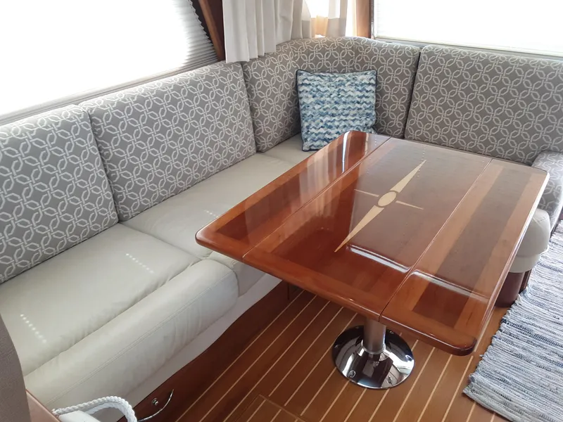 Slide: The Image of Interior seating area of 2016 Sabre 48 Salon Express with wooden table and patterned cushions. - 13
