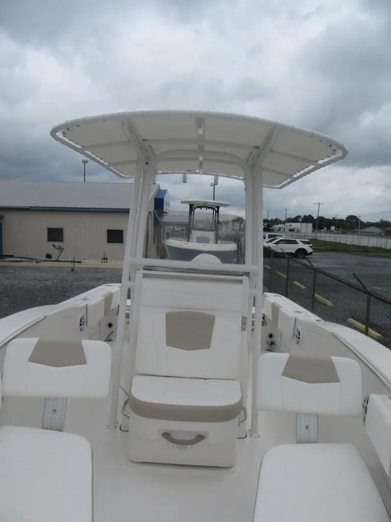 Slide: The Image of 2025 Robalo R200 Center Console boat with T-top, docked under cloudy skies. - 7