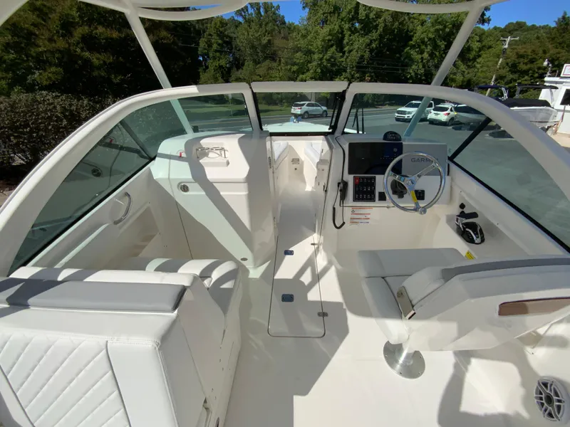 Slide: The Image of 2025 Pursuit DC 246 Dual Console boat interior with white seating and modern dashboard. - 11