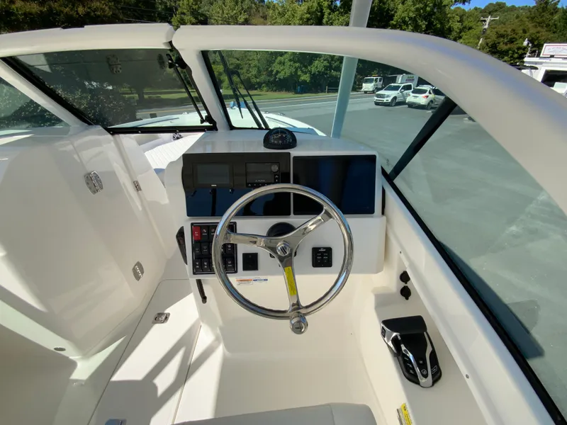 Slide: The Image of 2025 Pursuit DC 246 Dual Console boat cockpit with steering wheel and control panel. - 12