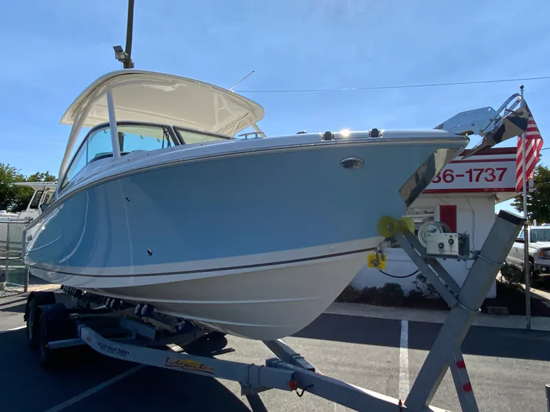 Slide: The Image of 2025 Pursuit DC 246 Dual Console boat on trailer, sunny day. - 2