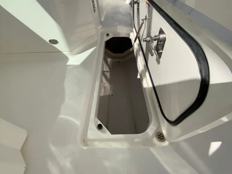 Slide: The Image of 2025 Pursuit DC 246 Dual Console storage compartment, open and empty, with white interior. - 28