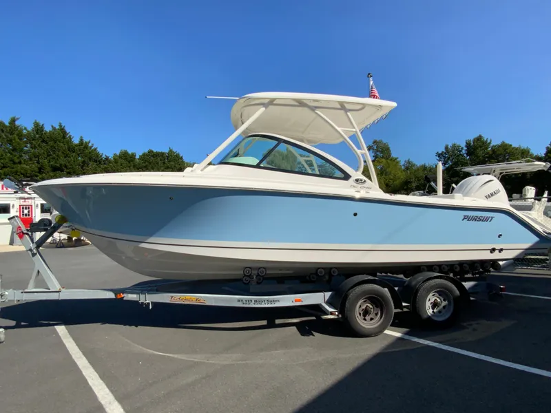 Slide: The Image of 2025 Pursuit DC 246 Dual Console boat on trailer, blue and white design. - 5
