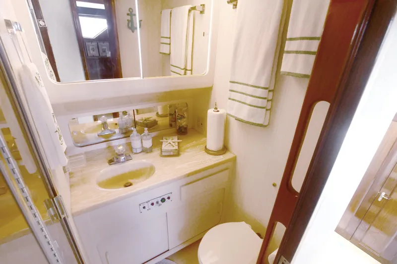 Slide: The Image of 1989 Hatteras 70 Cockpit Motor Yacht bathroom with sink, mirror, and towels. - 27