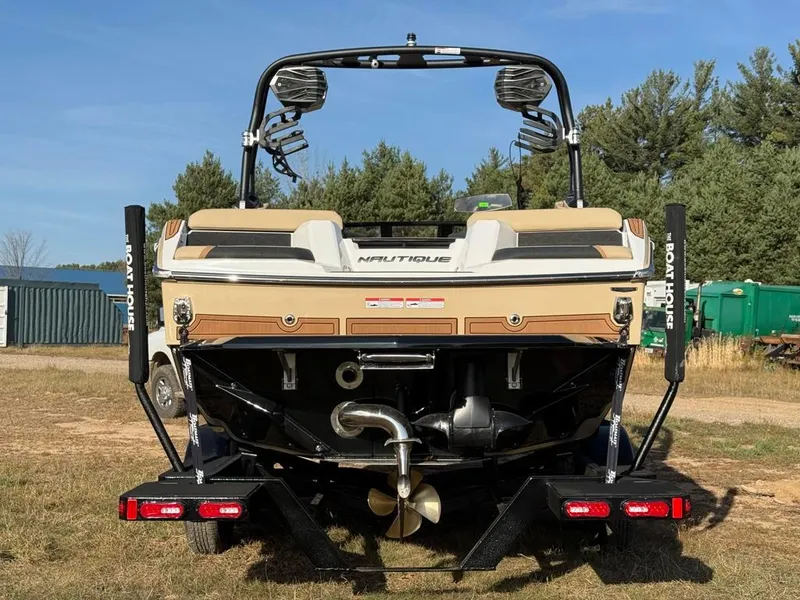Slide: The Image of 2025 Nautique Super Air GS22 boat rear view on trailer, outdoors. - 11