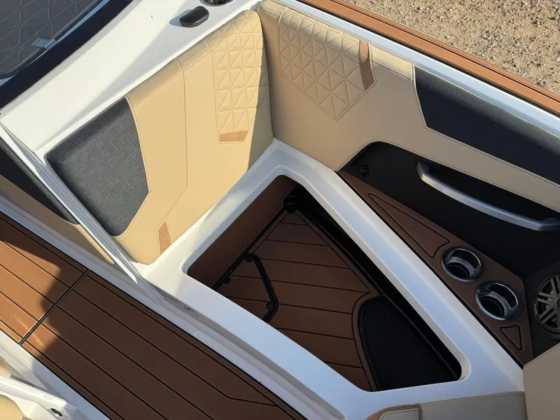 Slide: The Image of 2025 Nautique Super Air GS22 interior with tan and black seating, cup holders, and storage. - 15
