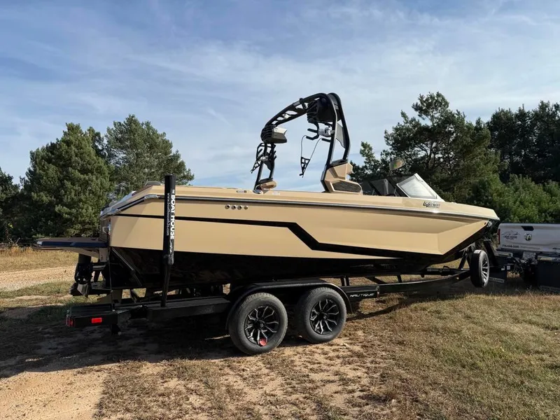 Slide: The Image of 2025 Nautique Super Air GS22 boat on trailer, parked outdoors. - 2