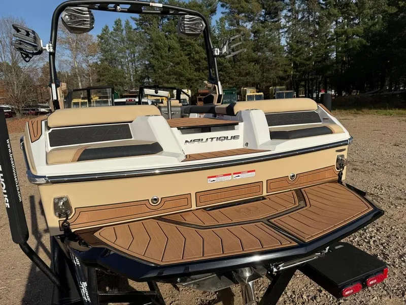 Slide: The Image of 2025 Nautique Super Air GS22 boat with teak deck, parked outdoors. - 45