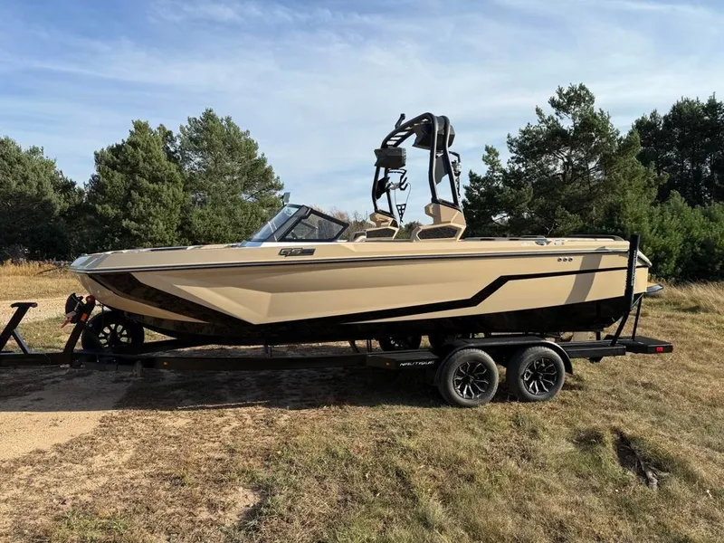 Slide: The Image of 2025 Nautique Super Air GS22 boat on trailer, parked on grass. - 6