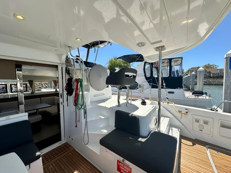 Slide: The Image of 2020 Lagoon 40 catamaran with spacious deck, seating area, and helm station, docked by the water. - 18