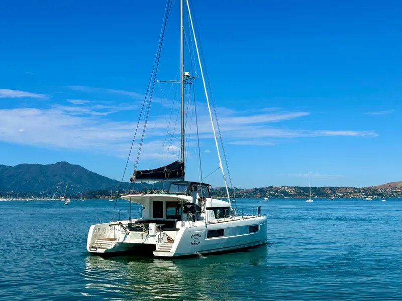 Slide: The Image of 2020 Lagoon 40 catamaran sailing on a calm sea with mountainous backdrop. - 2
