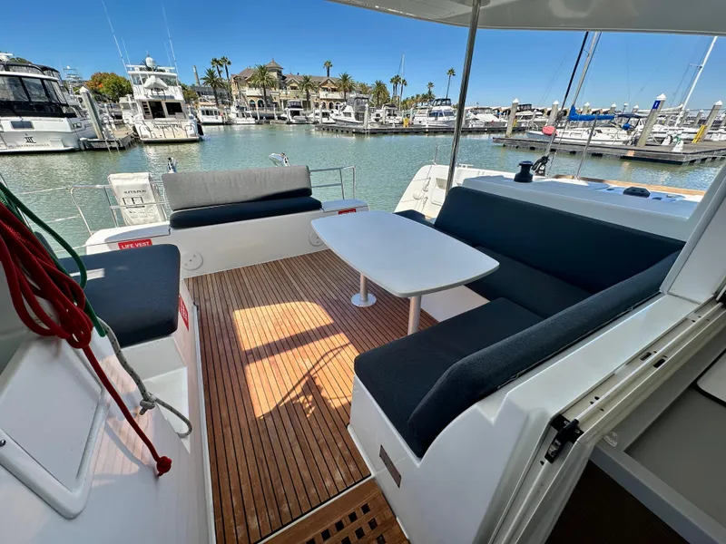 Slide: The Image of 2020 Lagoon 40 catamaran deck with seating and table, docked on calm water. - 29