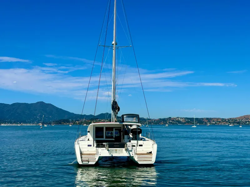 Slide: The Image of 2020 Lagoon 40 catamaran sailing on calm waters with scenic mountain backdrop. - 3