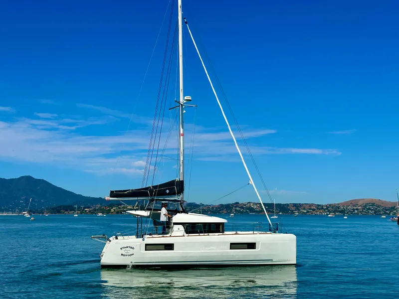 Slide: The Image of 2020 Lagoon 40 catamaran on calm water with scenic mountain backdrop. - 6