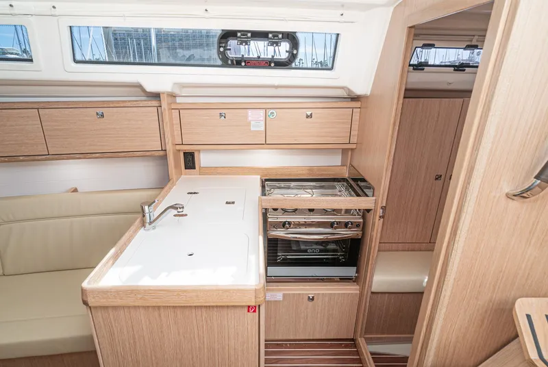 Slide: The Image of 2024 Bavaria Cruiser 34 yacht interior kitchen with stove, sink, and wooden cabinetry. - 30
