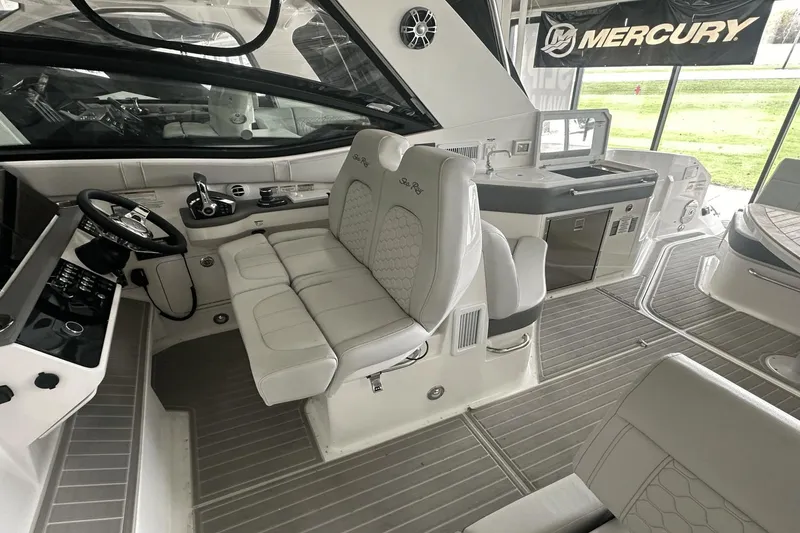 Slide: The Image of 2025 Sea Ray Sundancer 320 interior with helm, seating, and kitchenette, featuring Mercury branding. - 17