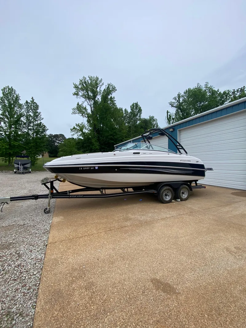 Slide: The Image of 2008 Four Winns F Series F244 boat on a trailer near a garage. - 3