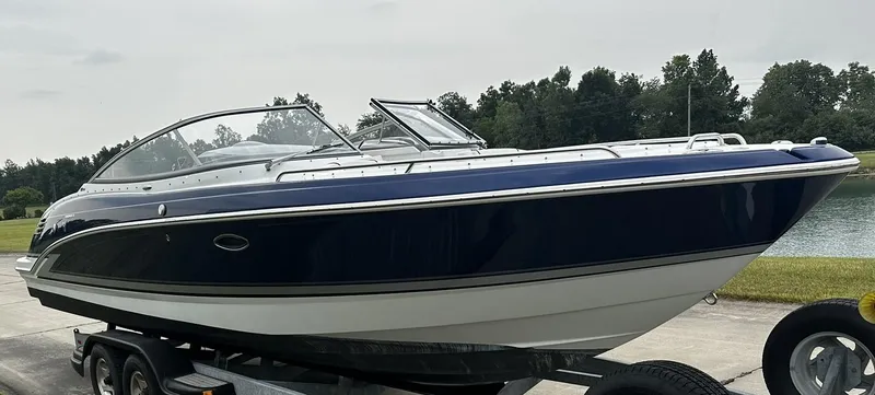Slide: The Image of 2013 Formula 270 Bowrider boat on a trailer near a lake. - 2