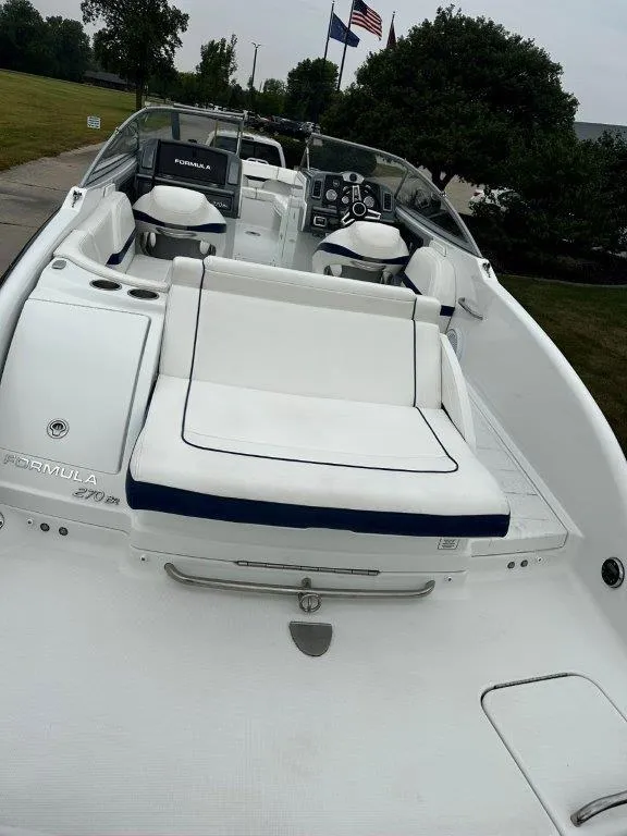 Slide: The Image of 2013 Formula 270 Bowrider boat with white and blue seating, docked outdoors. - 6