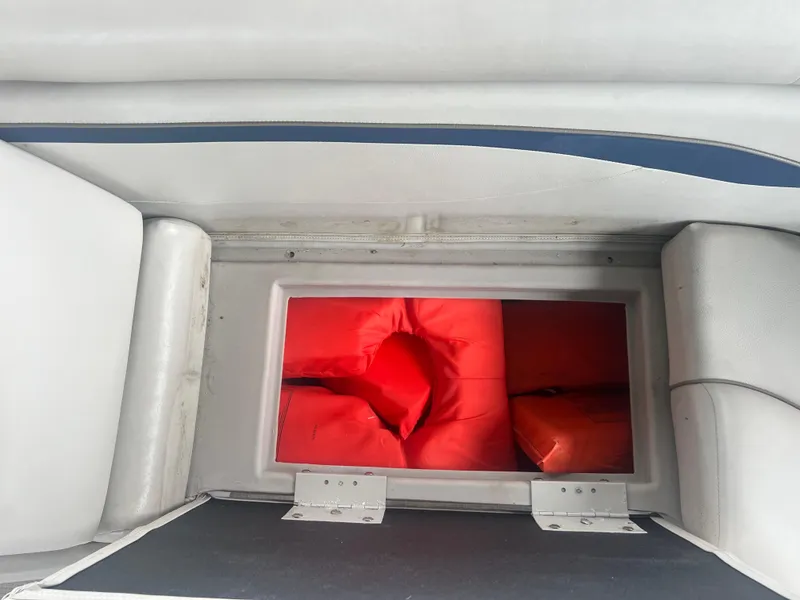 Slide: The Image of Storage compartment with red life jackets in a 2016 Bennington Sx boat. - 28