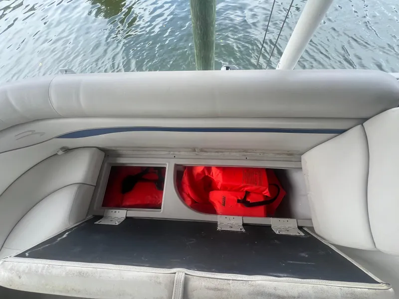 Slide: The Image of Storage compartment with red life jackets on a 2016 Bennington Sx boat. - 30