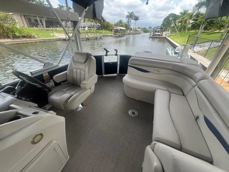 Slide: The Image of 2016 Bennington Sx boat interior with plush seating on a scenic canal. - 9