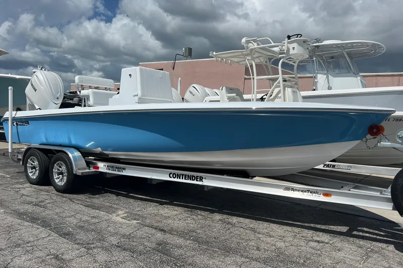 Slide: The Image of 2025 Contender 23 Bay boat on trailer, blue hull, parked outdoors. - 14