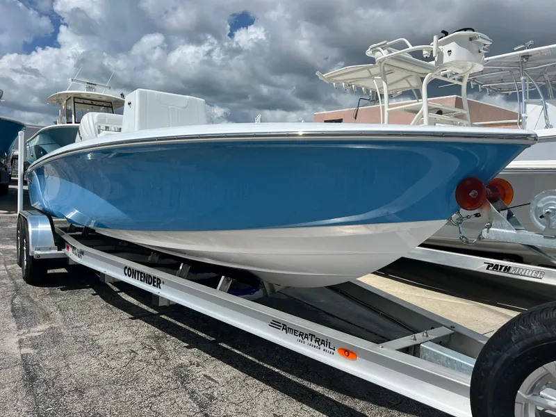 Slide: The Image of 2025 Contender 23 Bay boat on trailer, blue and white hull, docked at marina. - 9