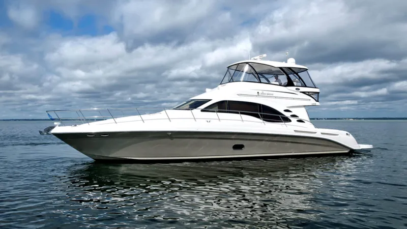The Image of 2006 Sea Ray 58 Sedan Bridge yacht on calm water under cloudy sky. - 1