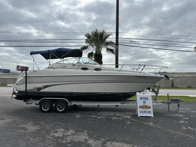The Image of 1999 Sea Ray 270 Sundancer boat on a trailer with a palm tree in the background. - 1
