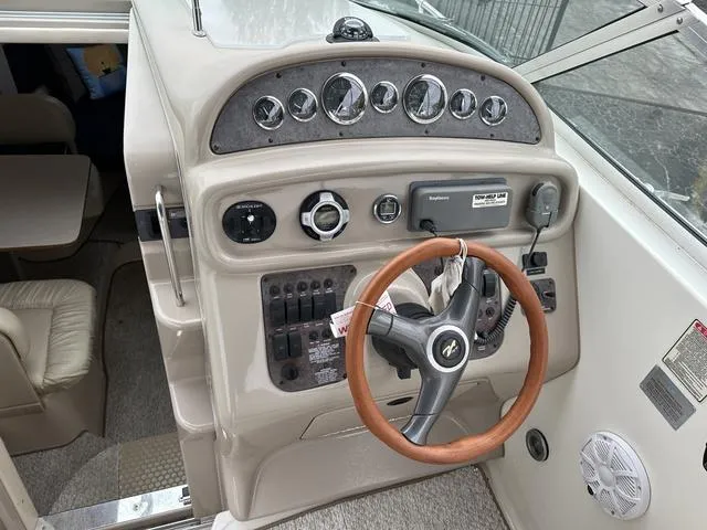 Slide: The Image of 1999 Sea Ray 270 Sundancer helm with gauges, controls, and steering wheel. - 12