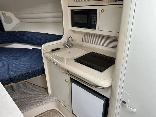 Slide: The Image of 1999 Sea Ray 270 Sundancer cabin interior with kitchenette and seating area. - 16