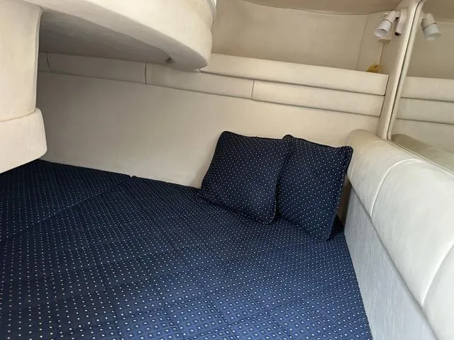 Slide: The Image of 1999 Sea Ray 270 Sundancer cabin interior with blue bedding and pillows. - 19