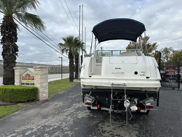 Slide: The Image of 1999 Sea Ray 270 Sundancer boat with black canopy, parked near palm trees. - 5